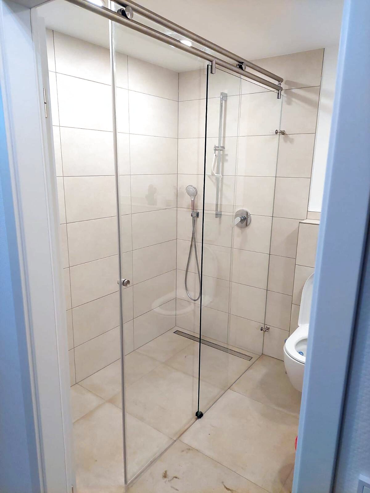 Bad mit bodengleicher Dusche, Glasschiebetür und großformatigen Fliesen
